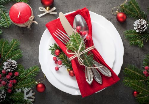 Christmas-themed table setting with festive decorations and red napkin.